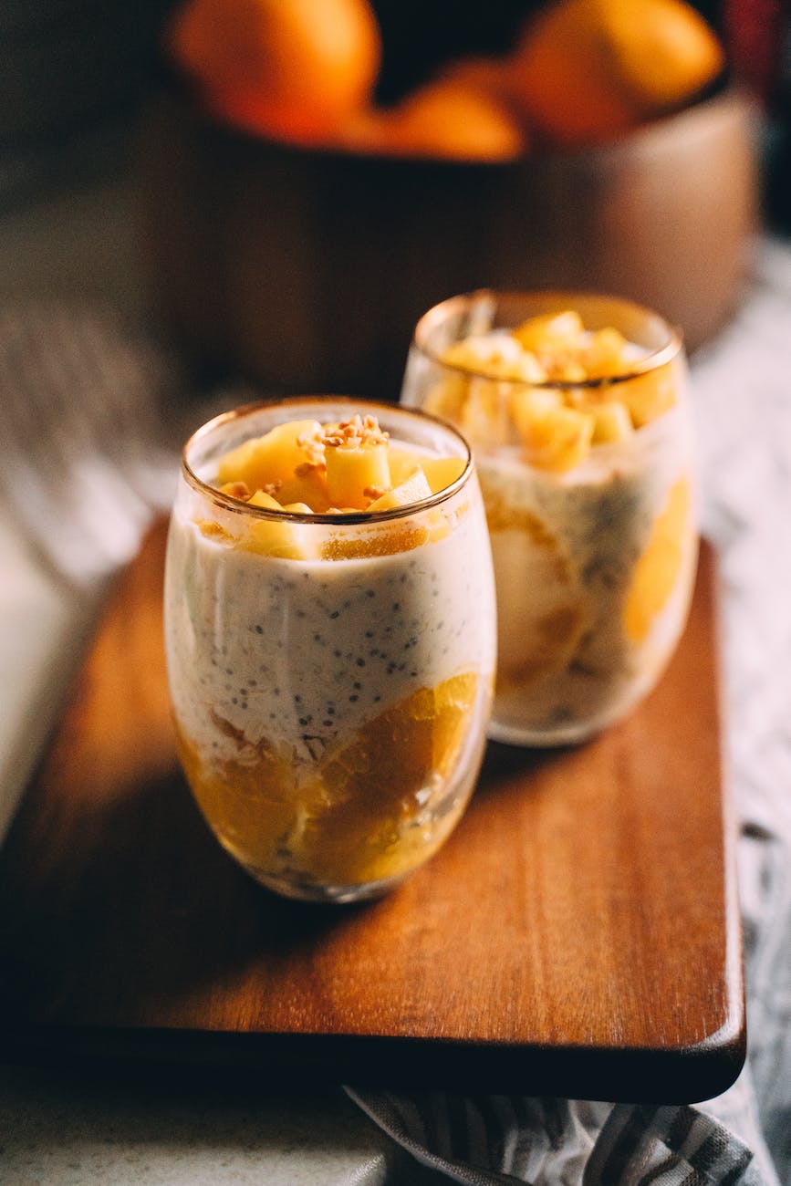 glasses of mango and orange chia pudding on wooden tray