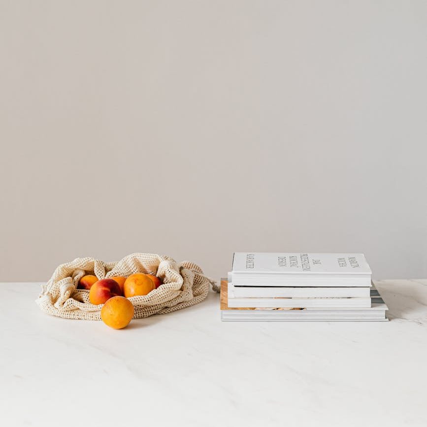 cotton sack with apricots near books on table