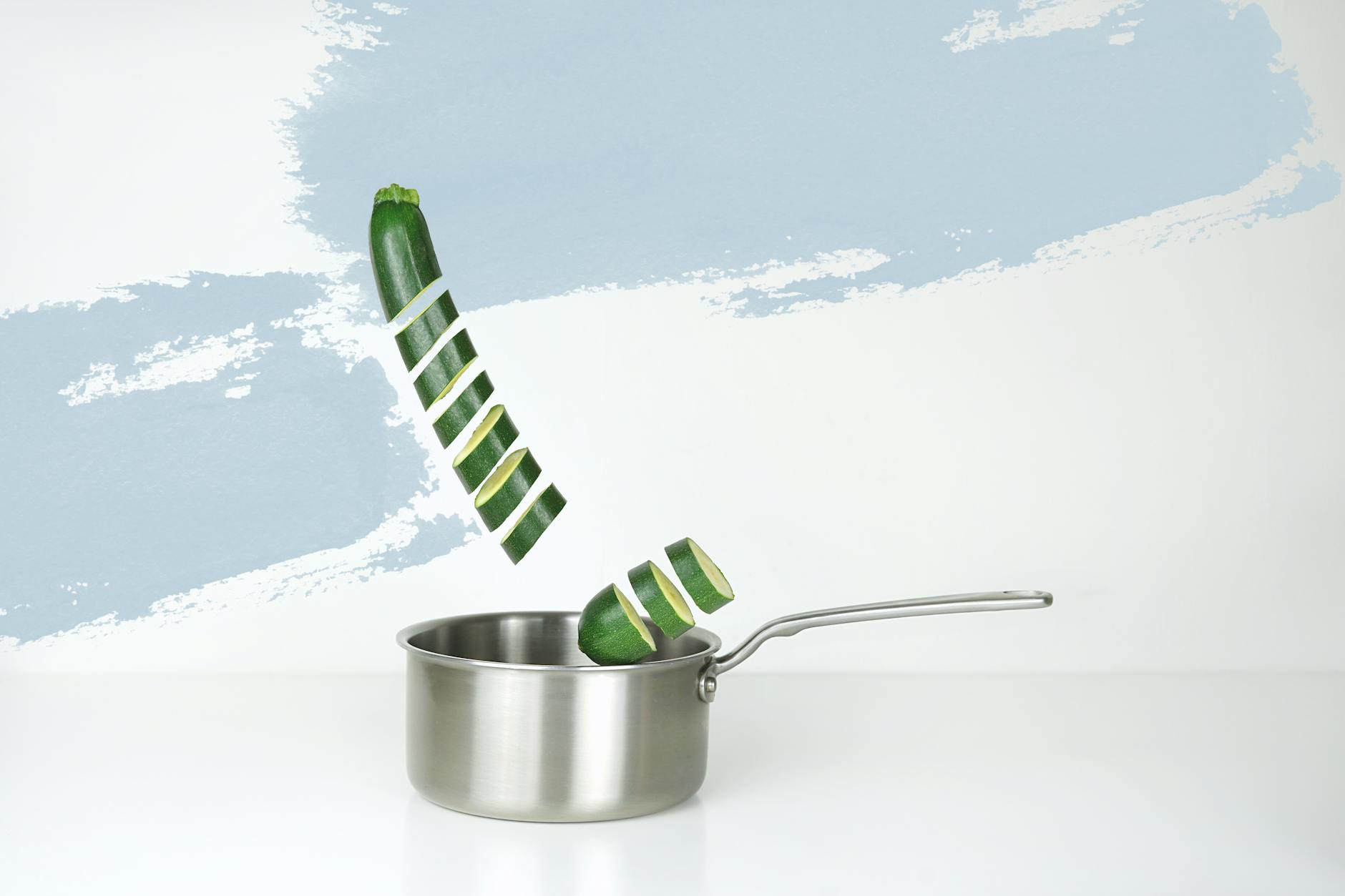 gray stainless steel sauce pan and green cucumber illustration